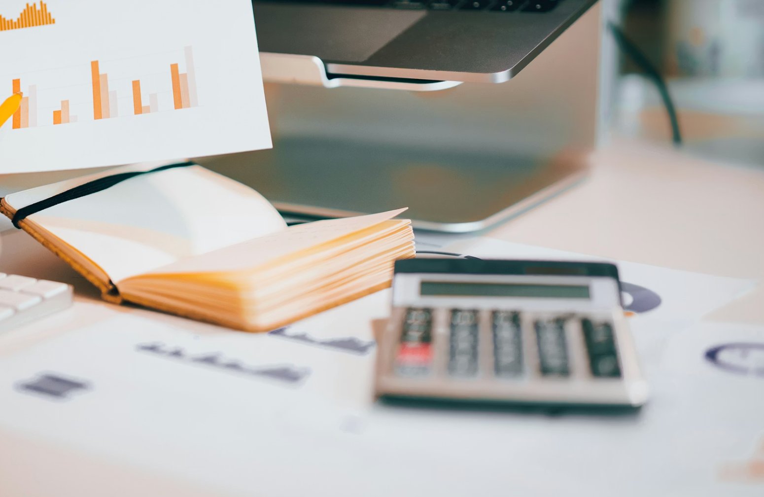 A notebook, bar chart printout, and calculator on a research desk, representing the fee analysis and comparison work that Advisor Facts compiles for New England wealth management firms